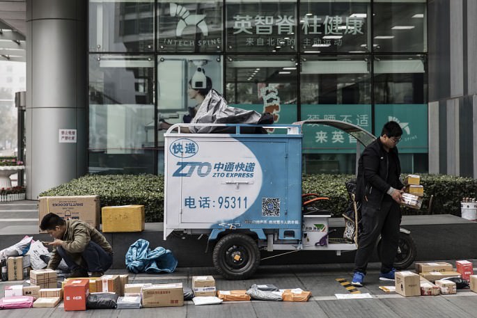 delivery-personnel-sort-out-parcels-beside-a-zto-express-delivery-vehicle-in-beijing